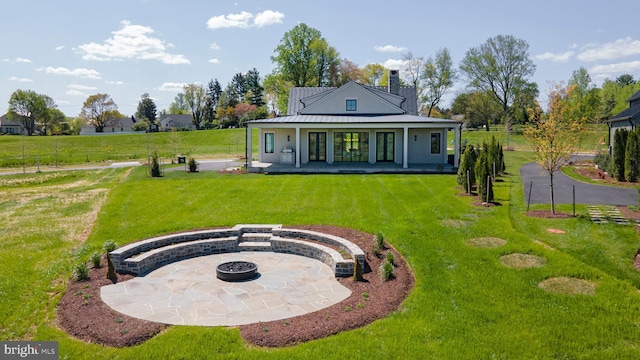 back of house with a porch, a fire pit, and a lawn