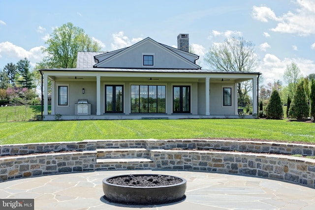 back of house featuring a patio area, ceiling fan, a yard, and a fire pit