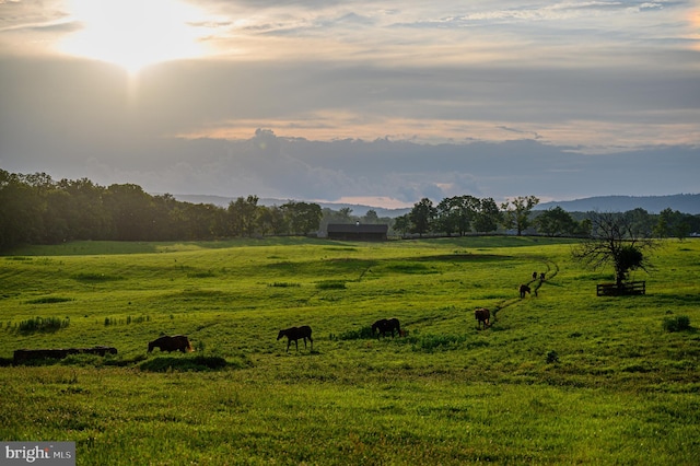 yard at dusk featuring a mountain view and a rural view