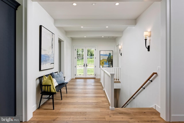 hall with beamed ceiling, light wood-type flooring, and french doors