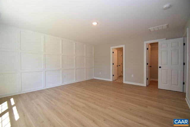 unfurnished bedroom featuring a walk in closet, light hardwood / wood-style flooring, and ensuite bath