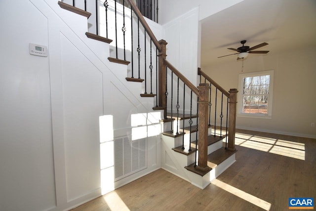 stairway featuring ceiling fan and hardwood / wood-style floors