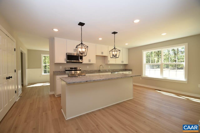 kitchen with a center island, sink, light hardwood / wood-style floors, white cabinetry, and stainless steel appliances