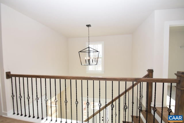 hallway with hardwood / wood-style floors and an inviting chandelier