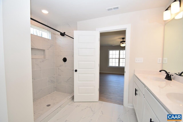 bathroom featuring ceiling fan, a healthy amount of sunlight, a tile shower, and vanity