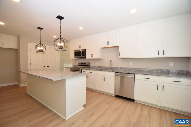 kitchen with light wood-type flooring, stainless steel appliances, sink, white cabinets, and a kitchen island