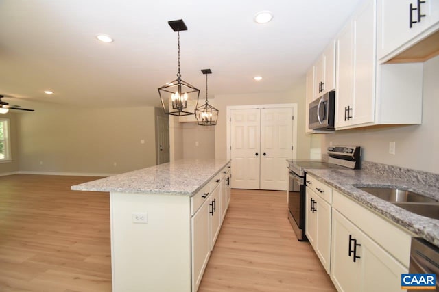 kitchen featuring light stone countertops, white cabinetry, a center island, appliances with stainless steel finishes, and light wood-type flooring