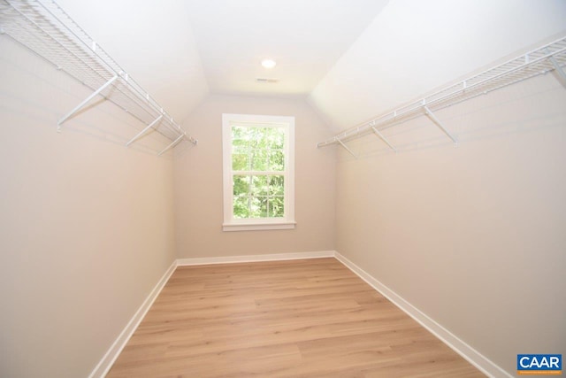 spacious closet featuring hardwood / wood-style floors and vaulted ceiling