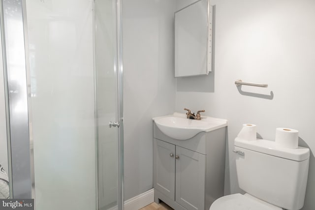 bathroom with a shower with door, vanity, and toilet