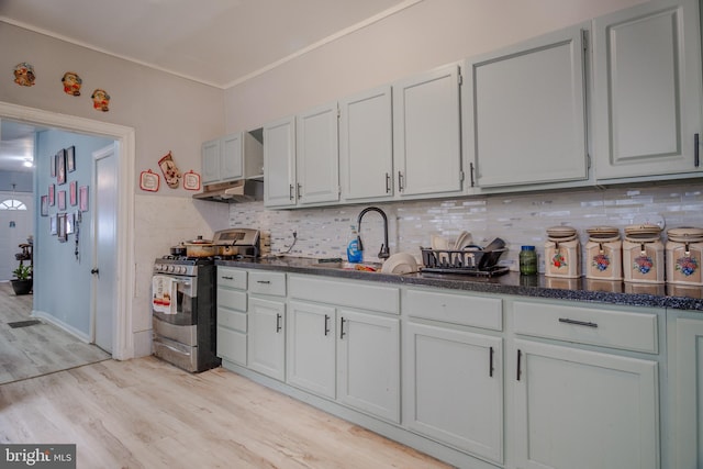 kitchen with backsplash, gas stove, sink, and light hardwood / wood-style floors