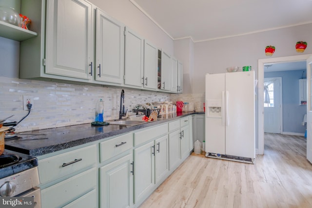 kitchen featuring stove, white fridge with ice dispenser, light wood-type flooring, backsplash, and sink