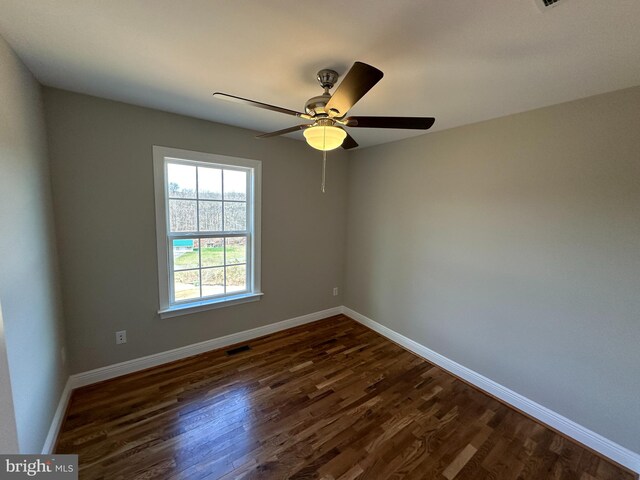 spare room with visible vents, ceiling fan, dark wood-type flooring, and baseboards