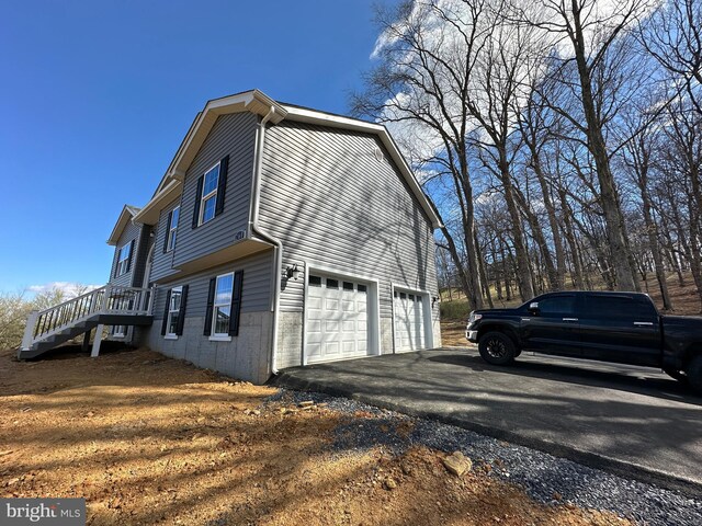 view of side of home featuring stairway, driveway, and an attached garage