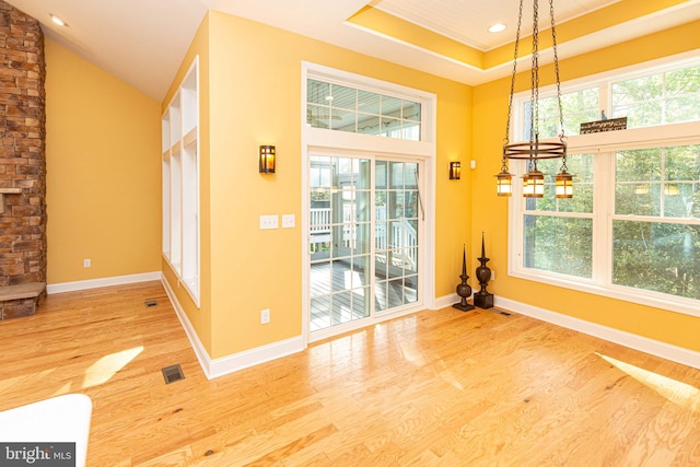 unfurnished dining area featuring hardwood / wood-style floors and a raised ceiling