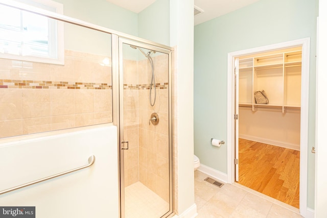 bathroom with tile patterned flooring, a shower with shower door, and toilet