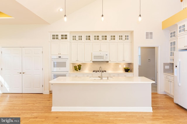 kitchen featuring a center island with sink, high vaulted ceiling, pendant lighting, and white appliances