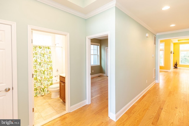 hallway with light wood-type flooring and ornamental molding