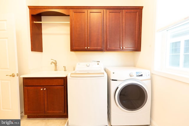 clothes washing area with washer and clothes dryer, cabinets, and sink