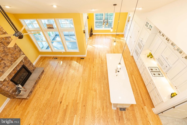 unfurnished living room featuring a stone fireplace, ceiling fan, and light wood-type flooring