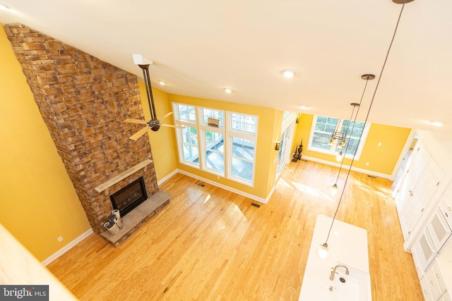 living room with a fireplace, light wood-type flooring, ceiling fan, and lofted ceiling