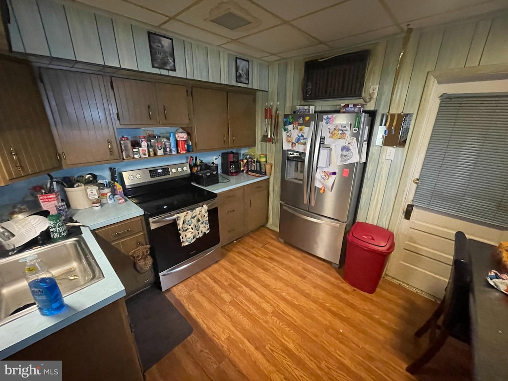 kitchen featuring a drop ceiling, appliances with stainless steel finishes, sink, and light wood-type flooring