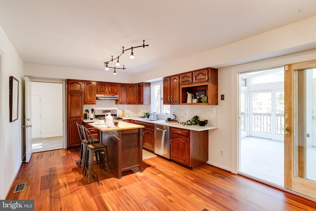 kitchen with a kitchen breakfast bar, a kitchen island, light wood-type flooring, and appliances with stainless steel finishes