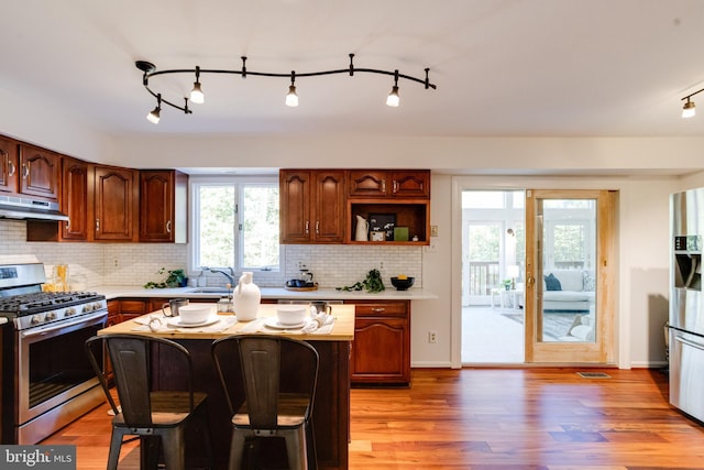 kitchen with a kitchen breakfast bar, a kitchen island, light hardwood / wood-style flooring, and gas range