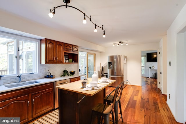 kitchen with a breakfast bar, sink, hardwood / wood-style flooring, appliances with stainless steel finishes, and a kitchen island