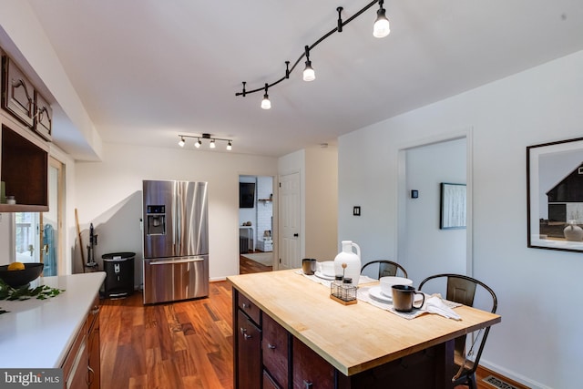 kitchen featuring dark brown cabinetry, dark hardwood / wood-style flooring, a kitchen island, and stainless steel refrigerator with ice dispenser