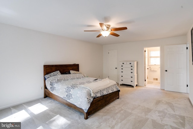 bedroom featuring light colored carpet, ceiling fan, and ensuite bathroom