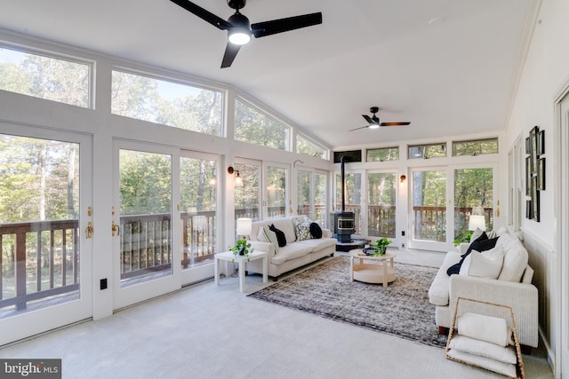 sunroom / solarium with vaulted ceiling, a wood stove, and ceiling fan