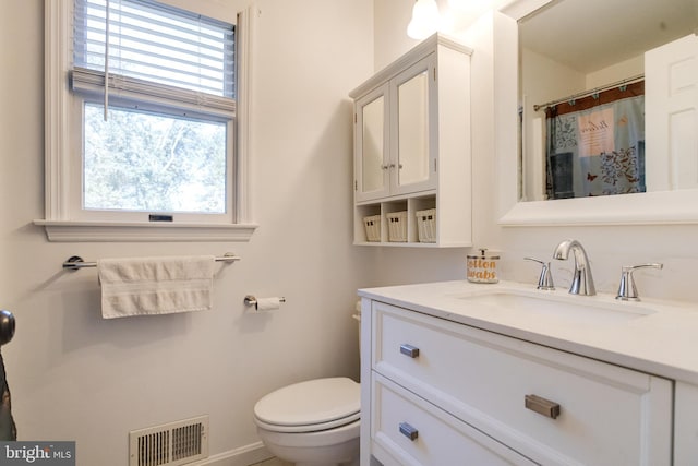 bathroom featuring a shower with shower curtain, vanity, and toilet