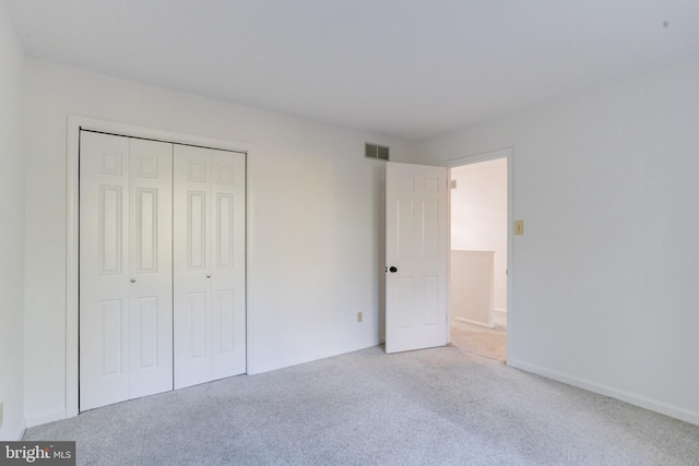 unfurnished bedroom with light carpet and a closet