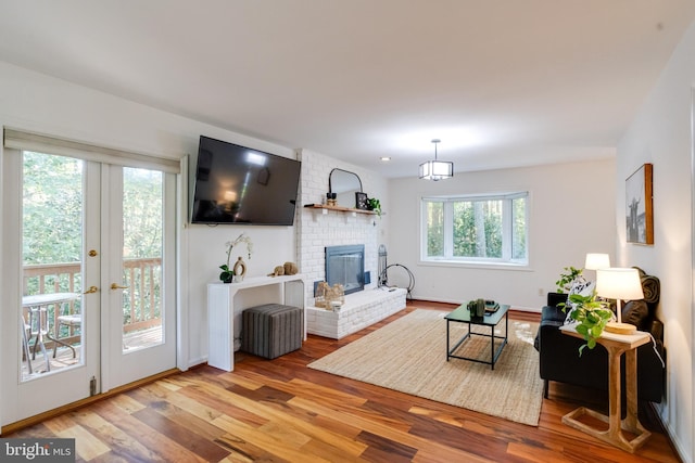 living room featuring a brick fireplace, french doors, and light wood-type flooring