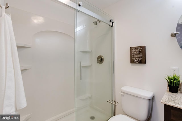 bathroom featuring vanity, an enclosed shower, and toilet