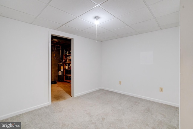 empty room featuring a paneled ceiling and light colored carpet