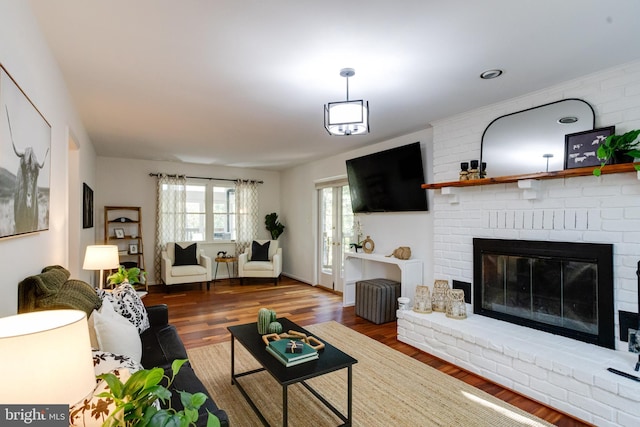 living room featuring dark hardwood / wood-style flooring and a brick fireplace