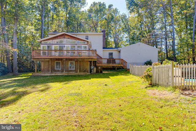 back of house featuring a yard, a wooden deck, and a sunroom