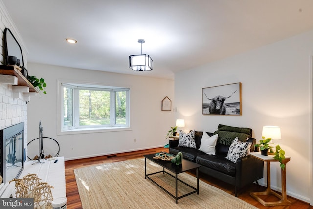 living room with wood-type flooring and a brick fireplace