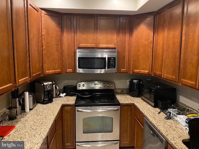 kitchen with appliances with stainless steel finishes and light stone counters