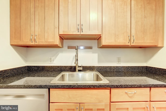 kitchen with dark stone countertops, light brown cabinets, white dishwasher, and sink