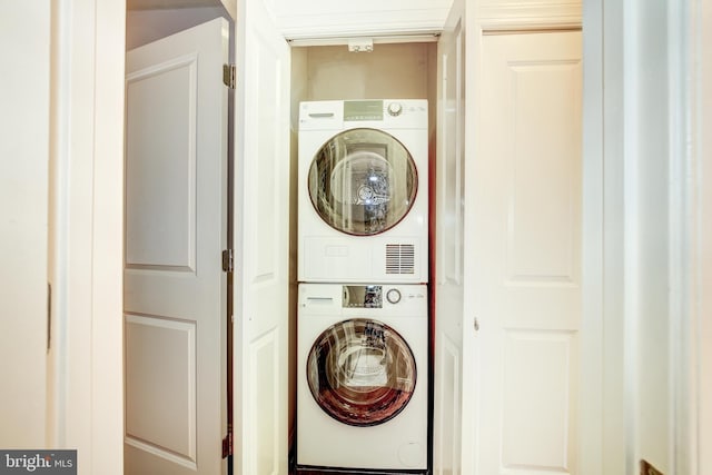 clothes washing area with stacked washing maching and dryer