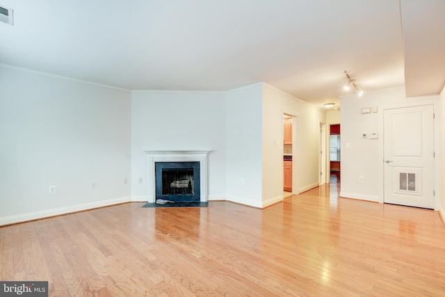 unfurnished living room with crown molding, track lighting, and light wood-type flooring