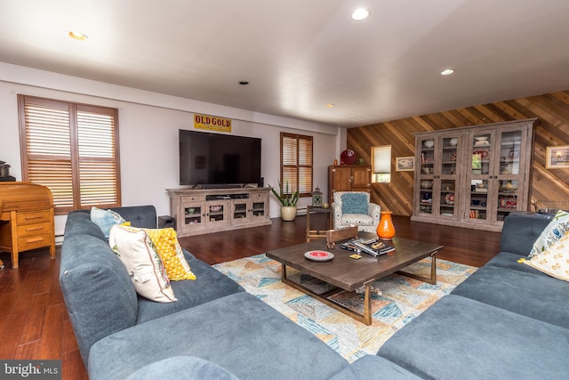 living room with dark wood-type flooring and wooden walls