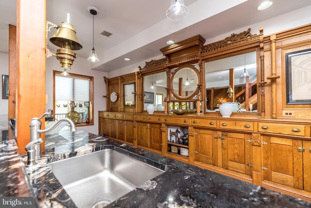 kitchen with decorative light fixtures, sink, and dark stone counters