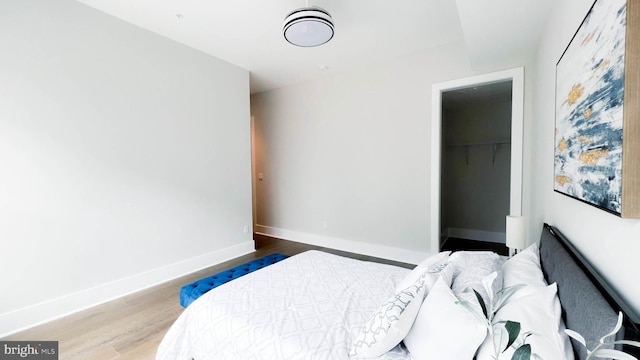 bedroom featuring a spacious closet, hardwood / wood-style flooring, and a closet