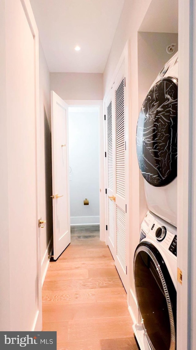 laundry room with stacked washer and dryer and light wood-type flooring