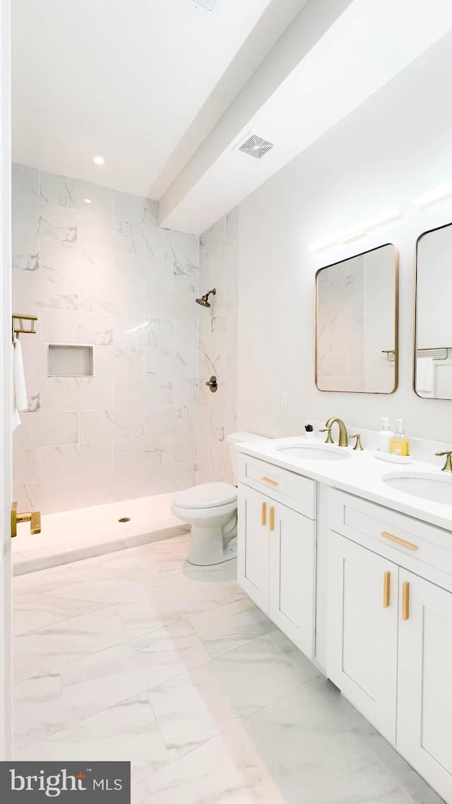 bathroom featuring vanity, a tile shower, and toilet