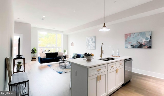 kitchen with dishwasher, a kitchen island with sink, sink, pendant lighting, and white cabinets