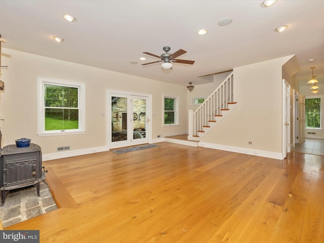 unfurnished living room featuring plenty of natural light, light wood-type flooring, and a wood stove